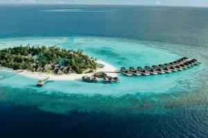 Luftaufnahme der Nova Maldives Insel mit Wasservillen und blauem Ozean.