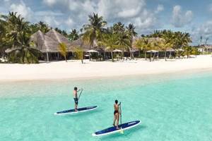 Zwei Personen paddeln auf blauen Brettern im klaren Wasser vor Nova Maldives.
