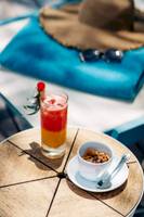 Cocktail auf einem Tisch im Nova Maldives Hotel mit einer Sonnenbrille und einem Hut im Hintergrund.