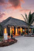 Außenansicht der Nova Maldives Grill House bei Sonnenuntergang mit beleuchteten Eingängen.