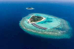Luftaufnahme der Nova Maldives Insel mit Wasserbungalows und blauem Wasser