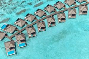Luftaufnahme des Nova Maldives Resorts mit Wasservillen und Stegen