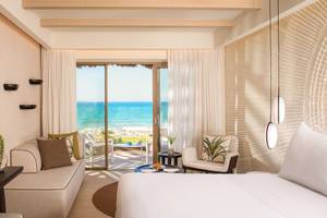 Mitsis Selection Rinela Hotel Suite mit Meerblick, großem Bett, Sofa, Tisch, Wein und Dekor.