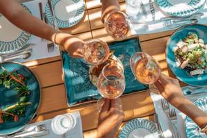 Mehrere Haende mit Weingläsern über einem Frühstückstisch im Mitsis Selection Rinela Hotel.