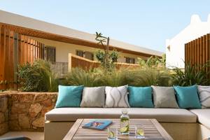 Außenbereich des Mitsis Selection Rinela Hotels mit einer Terrasse und einem Tisch.