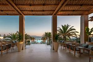 Terrasse des Mitsis Selection Rinela Hotels mit Blick auf Palmen und Meer