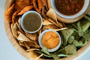 Eine Holzschale mit verschiedenen mexikanischen Chips und Saucen.