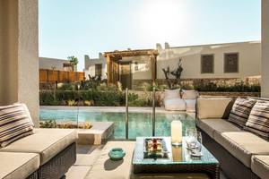 Außenbereich des Mitsis Selection Rinela Hotels mit Loungemöbeln, Swimmingpool und Garten