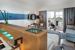 Innenansicht eines Hotelzimmers im Mövenpick Resort & Spa El Gouna mit Bett, Sofa und Meerblick