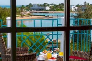 Frühstück auf dem Balkon im Mövenpick Resort & Spa El Gouna mit Blick auf den Ozean und eine tropische Landschaft.