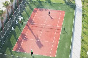 Zwei Personen spielen Tennis auf dem Tennisplatz im Freien im Defne Defnem Hotel.