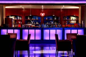 Innenansicht der Cocktailbar im Stella Gardens Resort & Spa Makadi Bay mit lila Beleuchtung und roten Stühlen