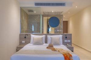 Hotelzimmer im Three Corners Equinox Beach Resort mit einem Bett, Kissen, Hut und Decken.