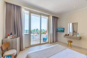 Innenansicht eines Zimmers im Three Corners Equinox Beach Resort mit Balkon, Fernseher und Blick auf den Ozean.