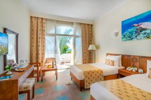 Zimmer im Three Corners Equinox Beach Resort mit zwei Betten, Tisch, Stuhl, Balkon und Meerblick