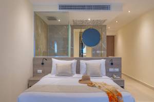 Schlafzimmer im Three Corners Equinox Beach Resort mit einem Bett, Kissen, einem Hut und einer Decke.