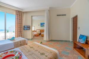 Zimmer im Three Corners Equinox Beach Resort mit zwei Betten, Fernseher und Meerblick.