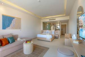 Suite-Interieur im Three Corners Equinox Beach Resort mit Bett, Sofa, Tisch und Fernseher.