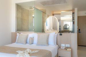 Schlafzimmer im Three Corners Equinox Beach Resort mit Bett und Badezimmerspiegel