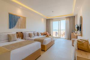 Zwei Betten in einem Hotelzimmer im Three Corners Equinox Beach Resort mit Blick auf das Meer.