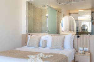 Schlafzimmer im Three Corners Equinox Beach Resort mit großem Bett, Dekor und Badezimmerspiegel