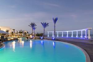 Ein Pool im Three Corners Equinox Beach Resort bei Nacht, beleuchtet von blauen Lichtern.
