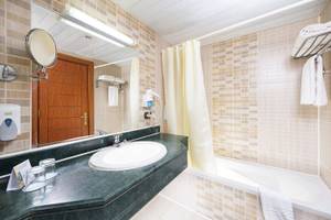 Badezimmer im Three Corners Equinox Beach Resort Hotel mit Waschbecken, Spiegel und Badewanne.