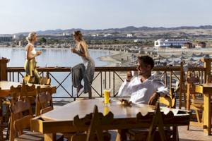 Drei Gäste sitzen auf der Terrasse des Three Corners Equinox Beach Resorts und genießen Getränke und Ausblick.