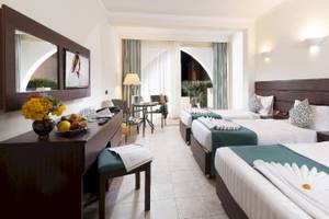 Drei Hotelzimmer im Three Corners Equinox Beach Resort mit Blumen, Obst und bequemen Betten.
