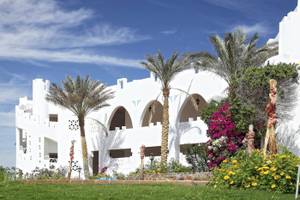 Außenansicht des Three Corners Equinox Beach Resorts mit weißen Gebäuden und Palmen