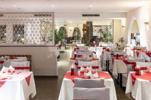 Restaurant-Innenbereich des Three Corners Equinox Beach Resorts mit gedeckten Tischen und roten Tischdecken.