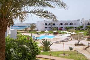 Außenbereich des Three Corners Equinox Beach Resorts mit Pool und Liegen.