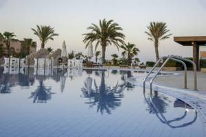 Schwimmbecken im Three Corners Happy Life Beach Resort mit Palmen und Sonnenliegen