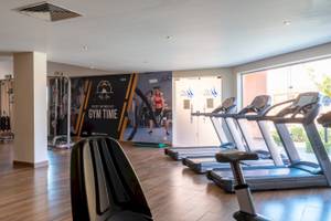 Fitnessstudio im Three Corners Happy Life Beach Resort mit Laufbändern und einer Werbung für Gym Time.