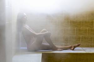 Frau in einem Dampfbad in einem Hotel, das in einer Sauna sitzt