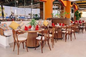 Innenbereich des Restaurants im Three Corners Happy Life Beach Resort mit runden Tischen und Stühlen.