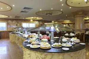 Buffet-Tisch im Three Corners Happy Life Beach Resort mit verschiedenen Kuchen und Obst.