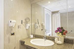 Badezimmer im Three Corners Happy Life Beach Resort mit Spiegel, Waschbecken und Blumenvase.