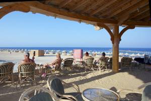 Gäste sitzen unter einem Pavillon am Strand des Three Corners Happy Life Beach Resorts.