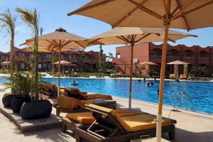 Ein Poolbereich im Three Corners Happy Life Beach Resort mit Liegestühlen und Sonnenschirmen.