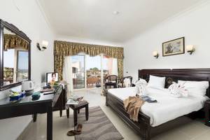 Hotelzimmer des Three Corners Happy Life Beach Resort mit Bett, Fernseher und Balkon.