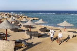 Familie am Strand des Three Corners Happy Life Beach Resorts mit großen Sonnenschirmen