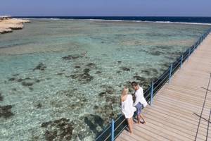 Aussicht auf das Drei Ecken Glückliches Leben Strand Resort mit zwei Personen auf einem Steg.