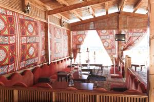 Innenbereich des Three Corners Happy Life Beach Resorts mit roten Sofas, Holztischen und bunten Wandbehängen.