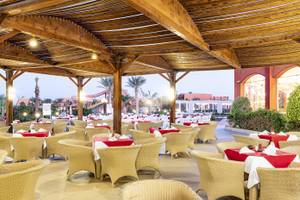 Restaurant im Three Corners Happy Life Beach Resort mit vielen gedeckten Tischen und Stühlen.