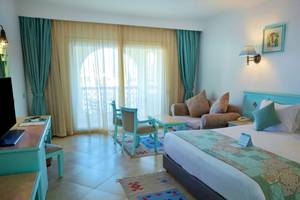 Das elegante Hotelzimmer im Sunrise Royal Makadi Resort mit moderner Einrichtung, großem Bett, Sofa und Schreibtisch.
