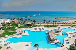 Luftaufnahme des Sunrise Royal Makadi Resorts mit Swimmingpool, Sonnenliegen und Blick aufs Meer.