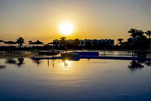 Sonnenuntergang am Gorgonia Beach Resort mit Swimmingpool und Palmen im Hintergrund.