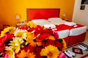 Doppelzimmer im Gorgonia Beach Resort mit zwei Betten, gelben und roten Blumen, und einem roten Kopfteil.