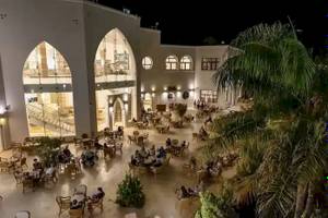 Außenbereich des Gorgonia Beach Resorts bei Nacht mit vielen Gästen an Tischen und Stühlen.